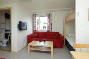 a living room with a red couch and a bed at Gullbrannagården in Halmstad