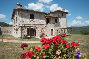 a stone building with red flowers in front of it at Agriturismo La Commenda-Adults Only in Cascia