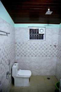a white bathroom with a toilet and a window at WildWood Stay in Madikeri +12 photos