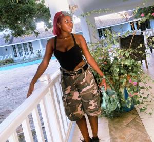 Eine Frau, die neben einem Zaun steht und Tarnshorts trägt. in der Unterkunft MoreExperiencesKgnCityCard in Kingston