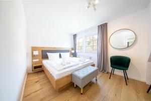 a bedroom with a bed and a mirror and a chair at Haus an der Düne Wohnung 9 in Lobbe