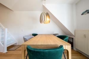 a dining room with a wooden table and green chairs at Haus an der Düne Wohnung 9 in Lobbe
