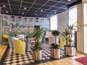 een restaurant met potplanten op een geblokte vloer bij ibis Rochefort in Rochefort