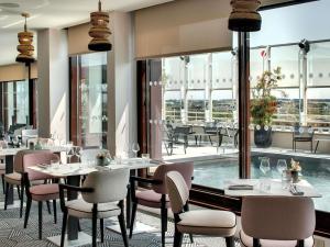 een restaurant met tafels en stoelen en een zwembad bij Pullman La Pléiade Montpellier Centre in Montpellier +148 foto's