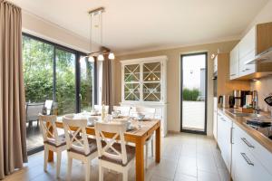 eine Küche mit einem Holztisch und weißen Stühlen in der Unterkunft Strandhaus Bernsteinsammler in Ostseebad Sellin