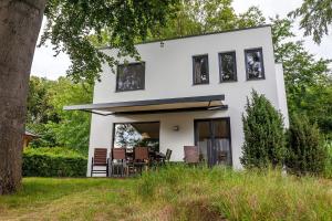 a white house with black windows and a tree at Strandhaus Wolkenlos in Ostseebad Sellin