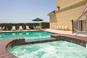 a swimming pool with chairs and an umbrella at Americas Best Value Inn - Gun Barrel City in Gun Barrel City