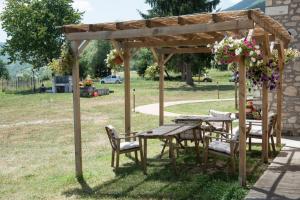 a picnic table and chairs under a wooden pergola at Agriturismo La Commenda-Adults Only in Cascia