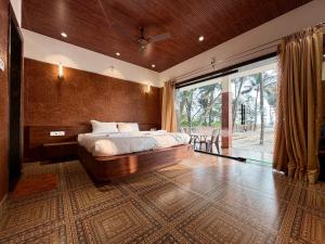 a bedroom with a large bed and a large window at Navasharada's White Sand Beach House in Udupi