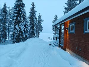 a snow pile next to a cabin in the woods at Villa Raanujärvi in Romakkaniemi