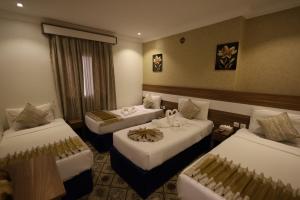 a hotel room with three beds with white sheets at Maysan AL Multaqa Hotel in Al Masfalah