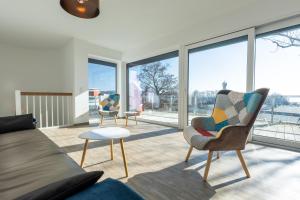 ein Wohnzimmer mit einem Sofa und Stühlen sowie großen Fenstern in der Unterkunft Penthouse Heimathafen in Lauterbach in Lauterbach