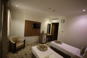 a hotel room with two beds and a chair at Maysan AL Multaqa Hotel in Al Masfalah +25 photos
