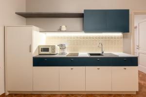 a kitchen with blue and white cabinets and a microwave at Nidin Apartments in Cassano Spinola