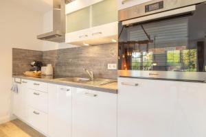 une cuisine avec des armoires blanches et un évier dans l'établissement Alte Fischfabrik SeePerle, à Lauterbach