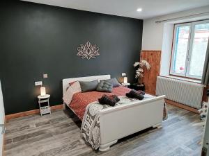 a bedroom with a white bed and a black wall at Cap Vosges 3 étoiles, Jeux et Balnéo, entre Vosges et Alsace in Plainfaing