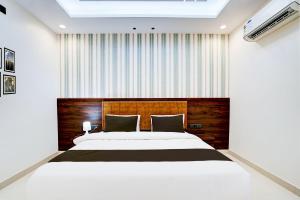 een slaapkamer met een groot bed met een houten hoofdeinde bij Townhouse Oak Ram Lala Mandir Kanpur Formerly Hotel Sun Rise in Kaliānpur