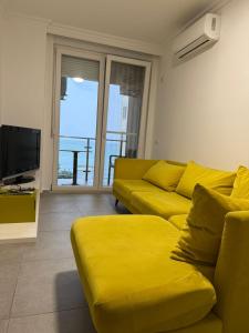 a living room with a yellow couch and a television at Shengjini holiday home beautiful in Lezhë