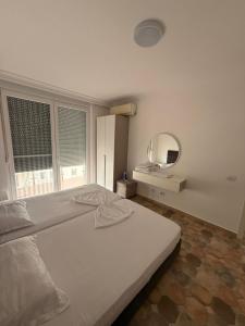 a white bedroom with a bed and a mirror at Shengjini holiday home beautiful in Lezhë +38 photos