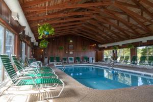 a swimming pool with green chairs in a building at Riviera Beach Resort in South Yarmouth