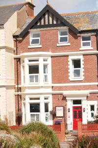 a red brick house with a red door at Pebbles House in Seaton