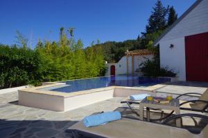 a pool with a table and chairs next to a house at Buddha Villa in Arillas