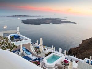 a villa with a pool and a view of the ocean at Iconic Santorini, a Boutique Cave Hotel in Imerovigli