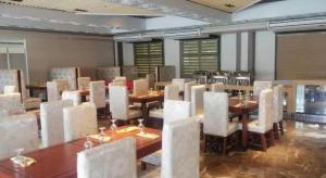 une salle à manger avec des tables et des chaises blanches dans l'établissement Big 8 Corporate Hotel Digos, à Aplaya