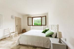 a white bedroom with a large bed and a window at Between sea and rocks in Porto Cervo