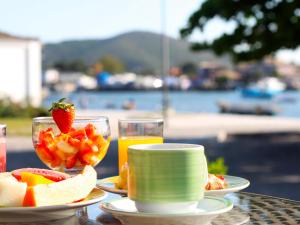 a table with plates of fruit and a glass of orange juice at Passagem Concept Hotel e Spa in Cabo Frio