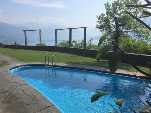 a blue swimming pool in a yard with mountains in the background at La Civetta by Fewotessin in Brissago