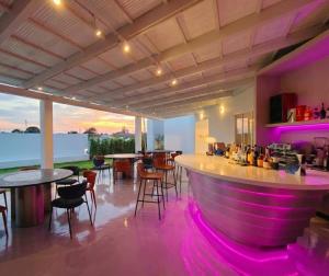 a bar with purple lighting in a room with tables and chairs at MITI TIKAAN villa in Ban Muang Chum