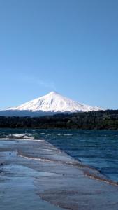 a snow covered mountain in the background of a body of water at Omi Kika B&B in Villarrica