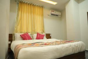 a bedroom with a large bed with red pillows at Hotel Rajpath Inn in Mahesāna +4 photos