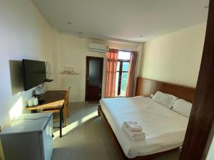 a bedroom with a bed and a tv and a table at JITRA RESORT in Sukhothai