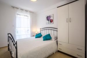 a white bedroom with a bed with blue pillows at Holiday Home Petra in Podstrana +65 photos