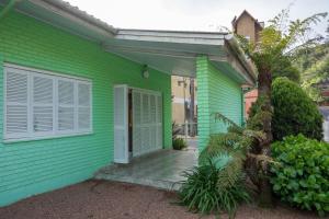 a green house with a door and a porch at Casa Rua Padre Carmene in Gramado