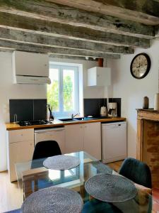 a kitchen with a table and a clock on the wall at La dépendance in Cour-Cheverny