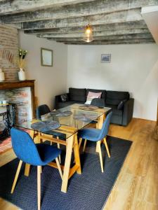a living room with a wooden table and blue chairs at La dépendance in Cour-Cheverny