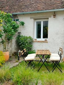 a table and two chairs in front of a house at La dépendance in Cour-Cheverny