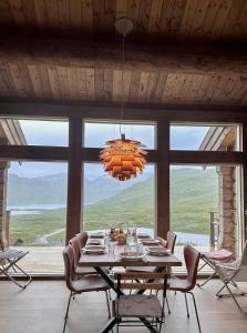 a dining room with a table and chairs and a chandelier at Spectacular Cabin With View In Jotunheimen in Eidsbugarden +28 photos