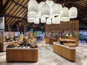 un ristorante con grandi lampadari e tavoli in una sala di Novotel Bali Benoa a Nusa Dua