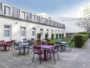 une terrasse avec des tables et des chaises devant un bâtiment dans l'établissement ibis Paris Gare de Lyon Ledru Rollin, à Paris