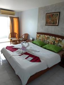 ein Schlafzimmer mit einem großen weißen Bett und grünen Kissen in der Unterkunft Kiengpiman Hotel in Mukdahan