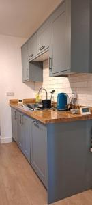 a kitchen with gray cabinets and a wooden counter top at Ground Floor Apartment, Garden and free parking - 10 The Rise in Kirkstall +13 photos