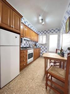 a kitchen with a white refrigerator and a table at On the Beach Oliva in Oliva