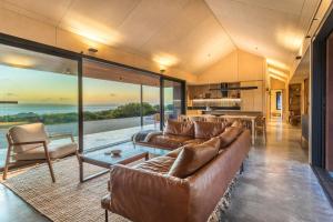 a living room with leather furniture and a view of the ocean at Native Dog Cabin in Bremer Bay