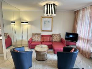 a living room with a red couch and chairs at Portofino by Fewotessin in Brissago