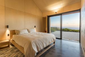 a bedroom with a large bed and a large window at Native Dog Cabin in Bremer Bay