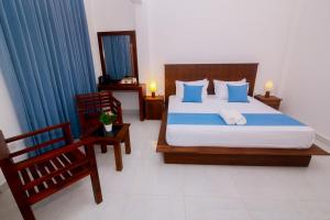 een slaapkamer met een bed met blauwe kussens en een stoel bij Ayana Resort Wilpattu in Anuradhapura